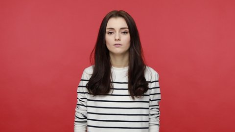 Portrait of woman holding hands on chest feeling acute pain in chest, risk of stroke, heart attack, wearing casual style long sleeve shirt. Indoor studio shot isolated on red background.