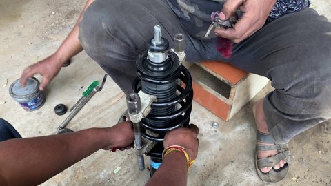 The mechanic performs the work of replacing the spring and shock absorber of the front suspension strut of the car.Repair and maintenance in a car service station.