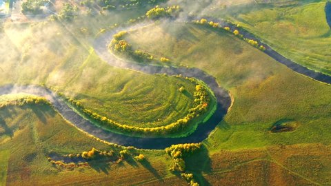 Top down view on exotic winding river flows through green wetlands. Birds eye view of zig-zag creek. Ukraine, Europe. Cinematic aerial shot. Discover the beauty of earth. Filmed in 4k, drone video.