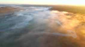 Shooting from a quadcopter in a foggy plain at dawn. Bird's eye view. Location place Horyn river, Ukraine, Europe. Cinematic aerial shot. Discover the beauty of earth. Filmed in 4k, drone video.