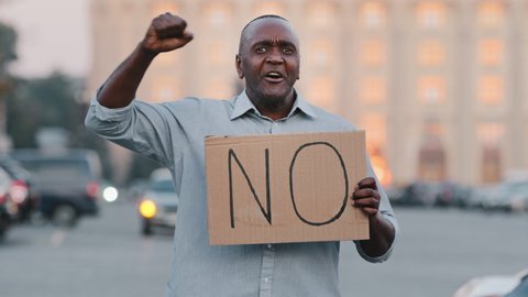 Stop concept. Black African American man protests against discrimination showing protest sign on strike. Protester immigrant person holding cardboard slogan banner with text no. Political unrest