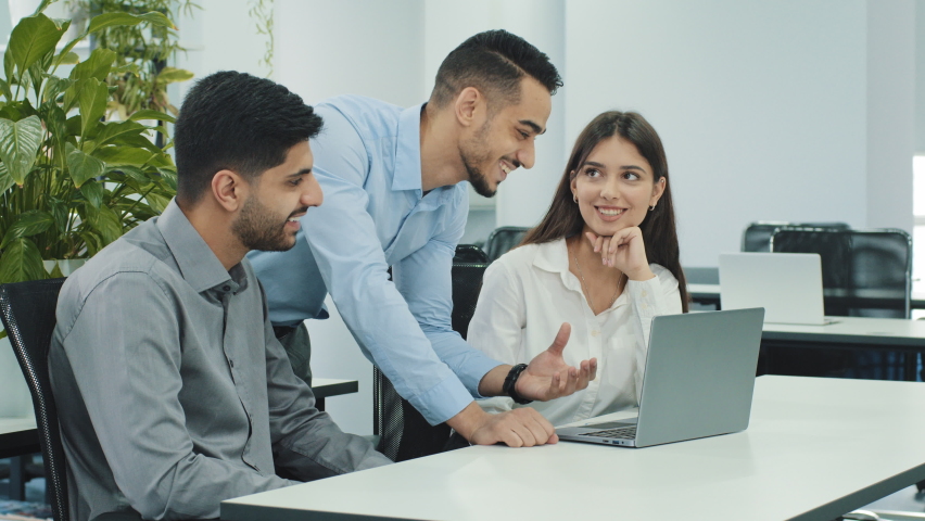 Multiethnic business team people brainstorm using laptop computer at workplace. Arabic, indian and mexican coworkers group discuss together corporate project software in teamwork at office desk Royalty-Free Stock Footage #1081486715