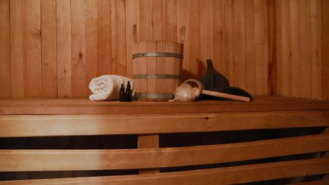 Traditional old Russian bathhouse SPA Concept. Interior details Finnish sauna steam room with traditional sauna accessories set basin towel aroma oil scoop felt. Relax country village bath concept.