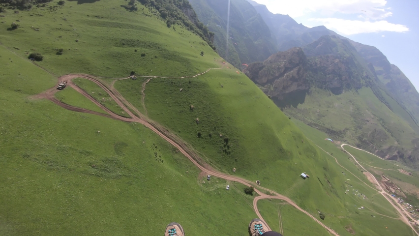 First Person Perspective Paragliding. Paragliding pilot fly paragliders among clouds and green mountains. Royalty-Free Stock Footage #1081488650