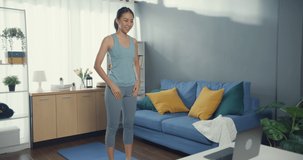Young attractive Asia woman in sportswear watching fitness online video on laptop practice yoga for beginner in living room at house. Home quarantine workout and fitness exercise without the gym.