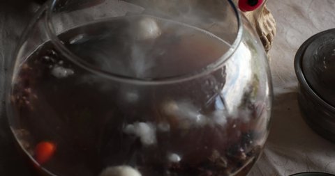 Disgusting bubbling brew in glass bowl of potion making for Halloween or magic ritual for Day of the Dead. Bubbles and smoke over cauldron of spooky poison mixture. Soft focus Halloween potion making