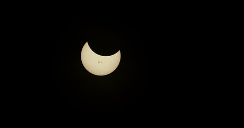 Crescent sun with prominent sunspots during a solar eclipse.