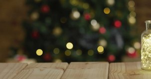 Animation of merry christmas text over blurred christmas tree in background. christmas, tradition and celebration concept digitally generated video.