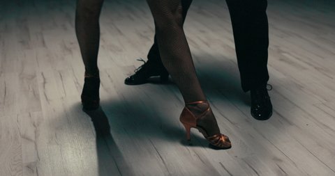 A shot of the dancers' legs, shapely legs of a woman in gold stilettos and black cabaret tights move sexily, gently, nimbly, a girl dancing with a partner in slippers