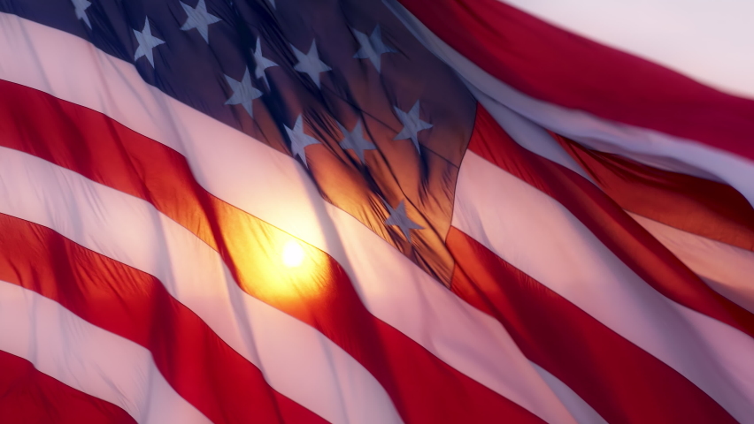 Epic cinematic flag of United States of America powerfully waving on wind with sunlight shining through flattering fabric. National symbol of freedom, power, independence. USA landmark background 4K