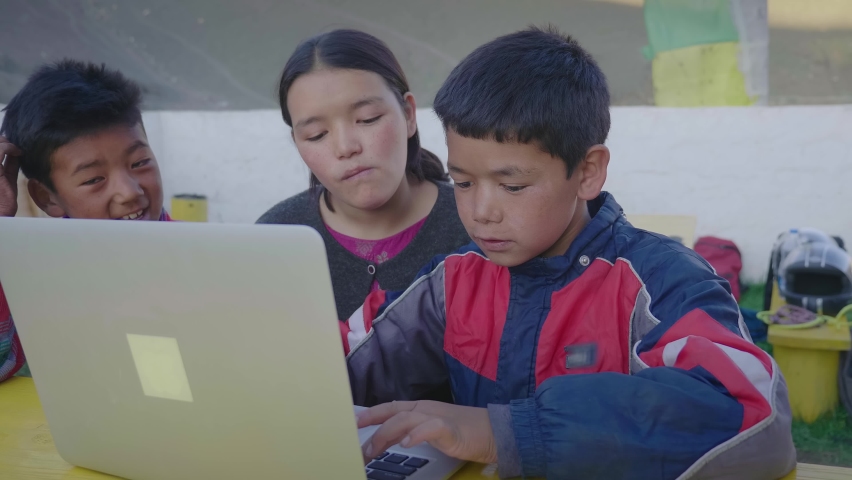 Three young East Asian rural kids sitting together outdoors completing a school project or an assignment together using a laptop in the mountainous rural village. Remote or distance education concept Royalty-Free Stock Footage #1081503299
