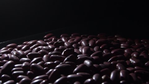 Red beans in a black tray gyrating with a intimate light, rotation