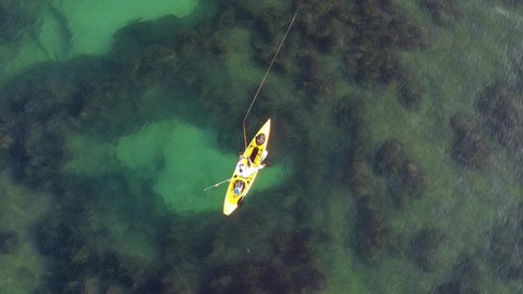 Kayak fishing, trolling fishing drone view. Fisherman trolling in kayak at mediterranean sea aerial shot during sunrise. Aquatic summer sports. Kayaker trolling and fishing at sea in his canoe.