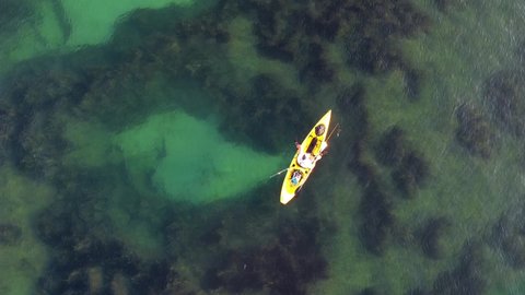 Kayak fishing, trolling fishing drone view. Fisherman trolling in kayak at mediterranean sea aerial shot during sunrise. Aquatic summer sports. Kayaker trolling and fishing at sea in his canoe.