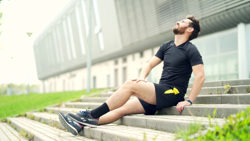 Young Caucasian runner athlete with muscle pain. Man massaging Stretching, trauma injury while jogging outdoors. Fitness male sprain severe pain stretch pull. Leg muscle cramp calf sport | Shutterstock HD Video #1081516082