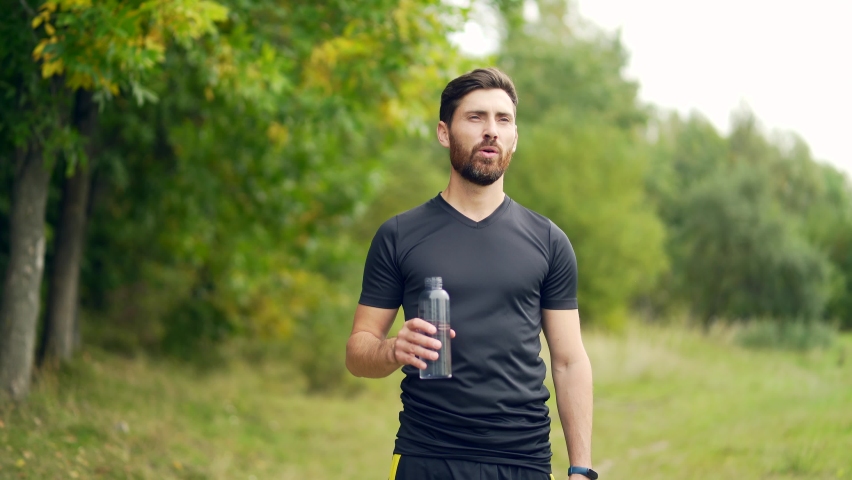 Tired exhausted dehydrated Athlete man runner drinking water bottle after workout. Sports bottle drink. male sportsman. runner sweaty and thirsty after difficult jogging outdoors in city park Royalty-Free Stock Footage #1081516367