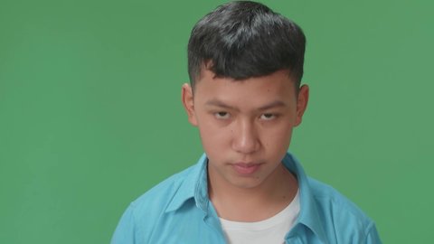 The Happy Young Asian Boy Waving Hand And Say Bye Bye While Standing On Green Screen In The Studio
