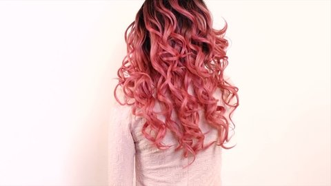 Beautiful long trendy pink ombre dyed curly Hair. Beauty woman with luxurious wavy black and pink gradient color hair. Brunette model girl with healthy Hair. Hairstyle, cure, extensions. Slow motion