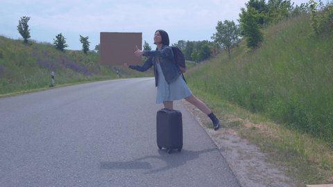 The concept of travel and hitchhiking. A young girl who hitchhikes and stops the car on the road.