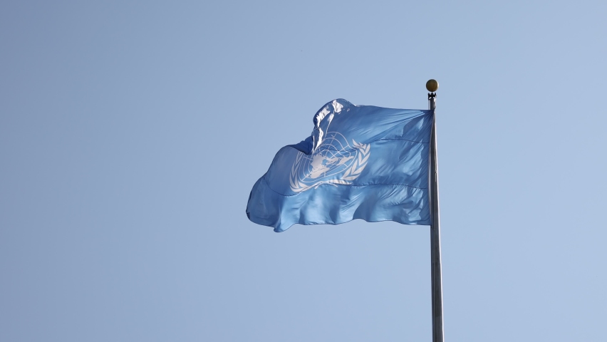 United Nations flag flying in the wind. UN blue flag waiving at a flagpole.