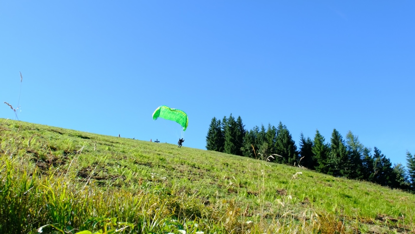 A paratrooper is running down hill, on his way to a magnificent jump above Austrian alps and lakes. a 4K video clip, Zwolferhorn, Austria.