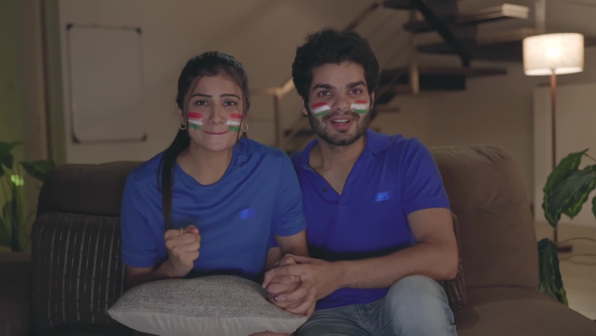 A young attractive couple is intense and nervous during a game or match of cricket on a television set. Indian Husband and wife having a good time together with the world cup game on TV | Shutterstock HD Video #1081552685
