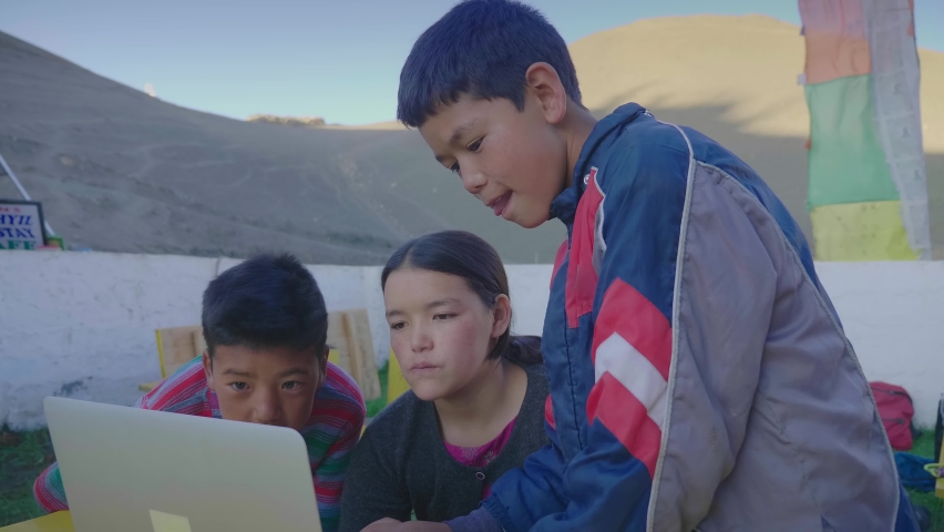 Three young East Asian rural kids sitting together outdoors completing a school project or an assignment together using a laptop in the mountainous rural village. Remote or distance education concept Royalty-Free Stock Footage #1081552691