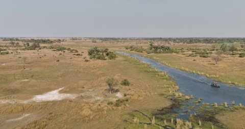 AFRICA,BOTSWANA,CIRCA 2021.Aerial view of tourists on a boat going down a river in the Okavango Delta, Botswana