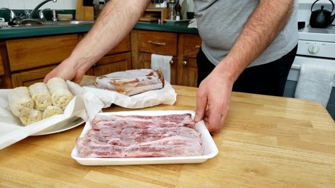 Home cooking - Removing or transferring frozen and or air sealed meat and food from wooden table to background.