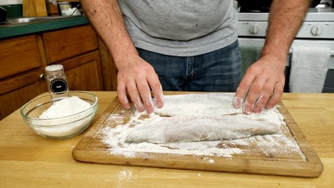 Home cooking - Seasoning two fillets of Walleye or Yellow Pike with salt and freshly ground black pepper getting fish ready top be batter in flour and cooked.