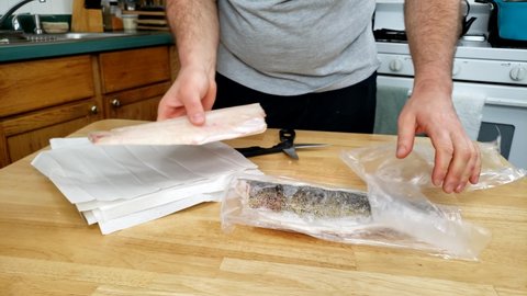 Home cooking - Unpacking air sealed two frozen walleye or Yellow Pike fillets ready to be thawed on paper.