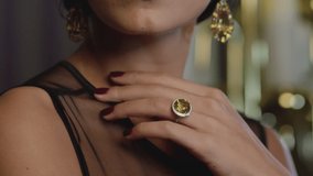 Beautiful brunette woman wearing  luxury expensive jewelry with yellow shining diamonds . Girl's hand slowly touching and caressing her beautiful white  neck and showing earring and ring . Closeup
