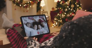 Asia people woman relax smile laugh greeting remotely talk to child kid friend at night online video call VoIP Merry Xmas eve festive party sit on cozy sofa at home enjoy good warm time winter season.