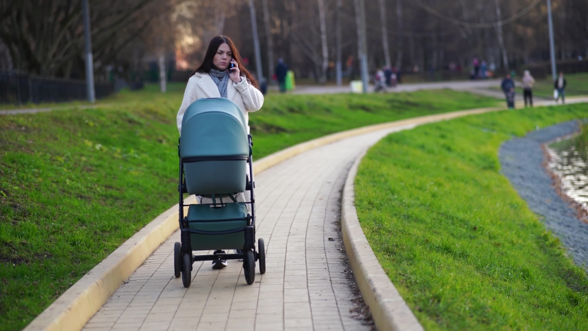 Mother with baby stroller on walk in the park by pond Royalty-Free Stock Footage #1081568174