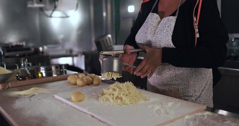 Woman using potato press for fresh handmade gnocchi inside pasta factory