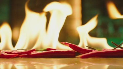 4K Close up shot of burning Red Chilli Peppers on table . Hot red chili peppers in flames on a restaurant background . Closeup , Slow Motion 