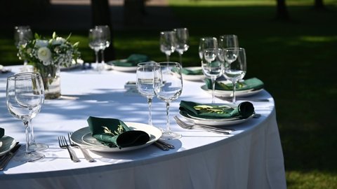 Outdoor banquet table set up served dinner tableware and silverware. Wide footage.