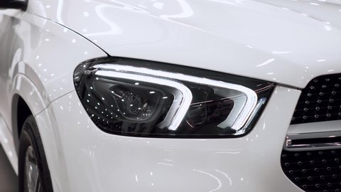 Close up of details of headlights of anonymous prestigious white luxury modern car. Concept of passion for driving cars, car dealerships,luxury cars. Shot in 4K. Head light.