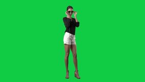 Stylish young ponytail elegant woman fashion model posing with sunglasses in slow motion. Full body isolated on green screen background - Powered by Shutterstock - Get 15% off with code: PIKWIZARD15
