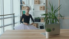 Cute Girl Ballerina Learns the Basics of Rhythmic Gymnastics or Ballet Using a Laptop Online in the Living Room at Home. Dance Class Online For Teenage Girls. A Lesson in Ballet Dancing.