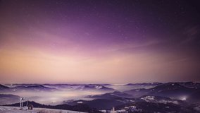 Night starry sky over village in Carpathians, view from above, 4k UHD video timelapse