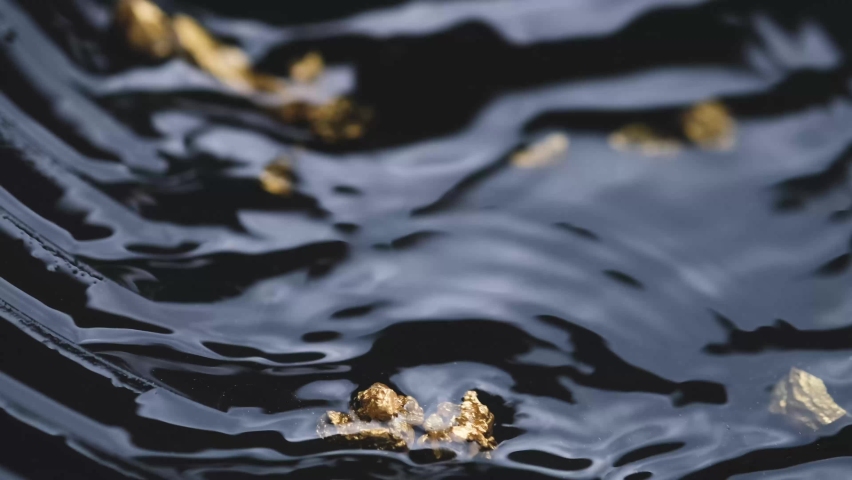 man's hand is picking up a nugget of pure gold sifted from a mine or a natural water source.