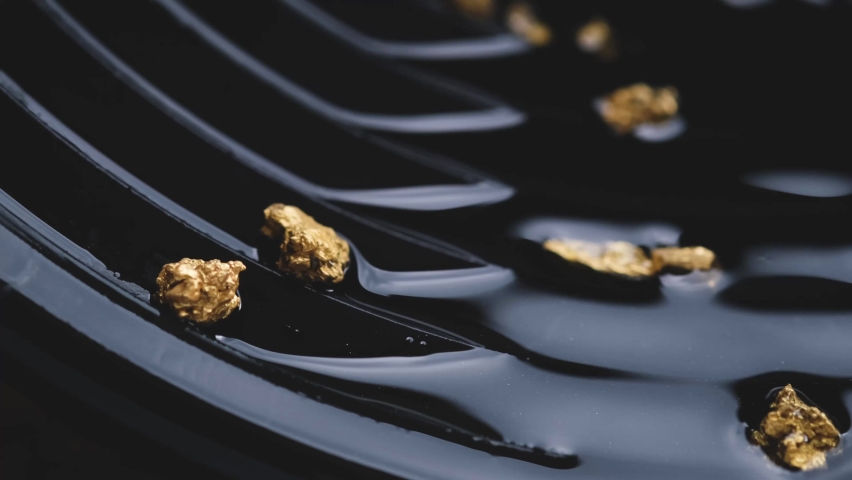 man's hand is picking up a nugget of pure gold sifted from a mine or a natural water source.