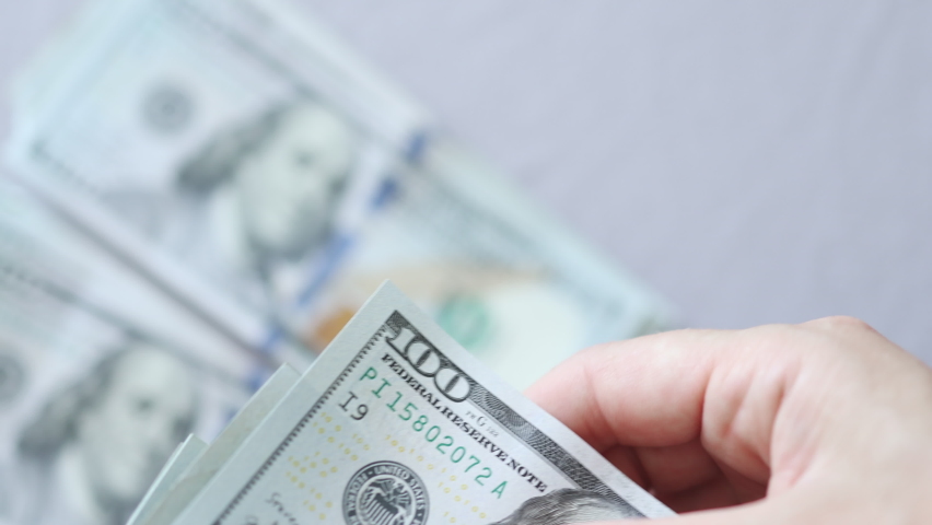 recounting hundred dollars banknotes bills with bunches of money on a light background