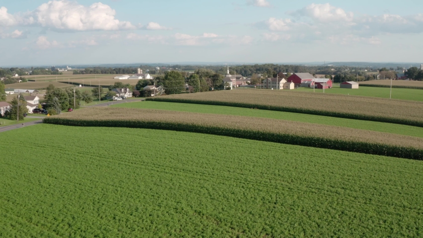Aerial of homes in rural America. Beautiful summer drone shot. Red barn, roads, green fields. Cinematic beautiful scene.