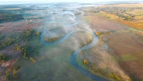 Top down view on winding river and fog rolling over plain from a bird's eye view. Location Horyn river, Ukraine, Europe. Cinematic aerial shot. Discover the beauty of earth. Filmed in 4k, drone video.