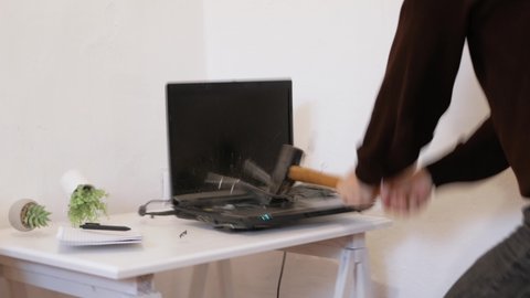 The man smashed laptop with hammer. Error, does not turn on, system crash. person is upset tired stressed, depressed, sad, angry psycho. Broke computer, destroyed, crazy. office worker. unbearably