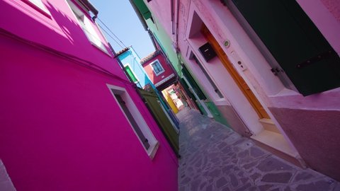 Narrow street in shadow between colorful houses in Burano