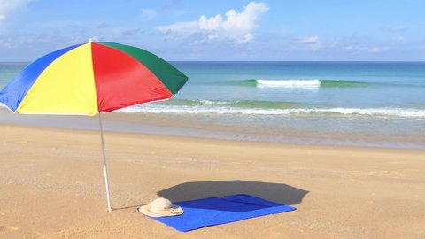 A beautiful morning Phuket beach with brightly colored umbrellas and towels laid on the beach.	