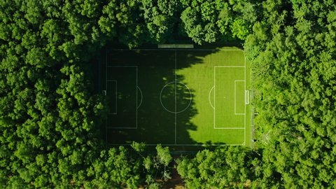 Cinematic straight down aerial shot of beautiful soccer field hidden in green park or national forest. Empty football playground. Amazing sport location and destination for workout
